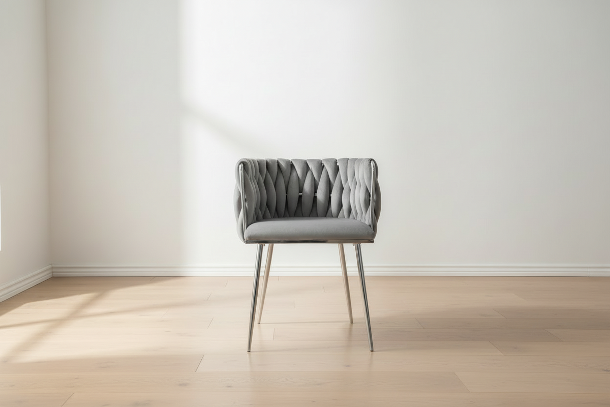 Gray upholstered chair in a minimalistic room with light wood flooring and white walls.
