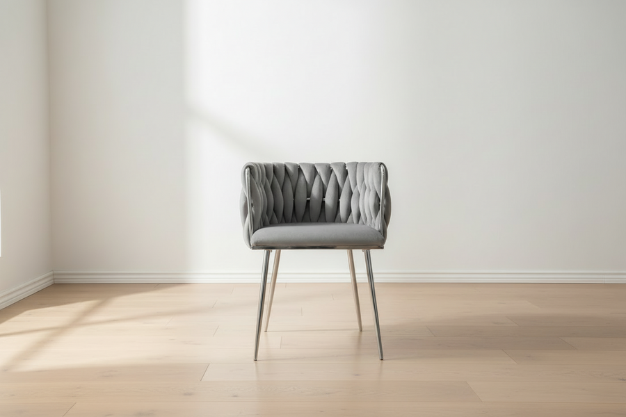 Gray upholstered chair in a minimalistic room with light wood flooring and white walls.