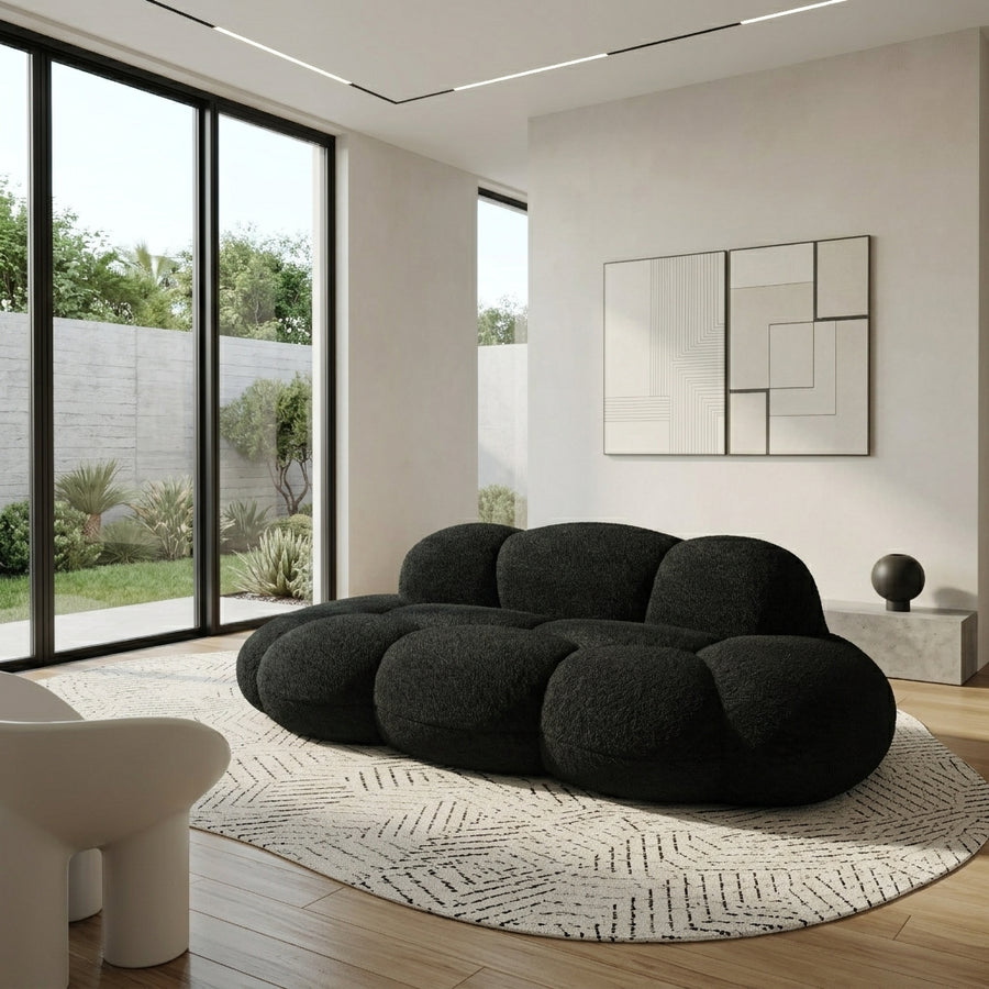 Black boucle cloud sofa with rounded bubble cushions on a round rug in a modern living room