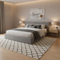 A modern platform bed frame with a gray upholstered headboard and base, supported by light wood slats, photographed in a warehouse or showroom setting.