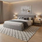 A modern platform bed frame with a gray upholstered headboard and base, supported by light wood slats, photographed in a warehouse or showroom setting.