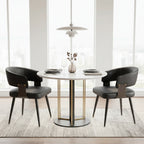 Dining room with a round table and black chairs, featuring a modern light fixture and abstract art on the wall.