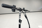 Close-up of a black electric scooter handlebar assembly with a textured grip, brake levers, and wiring on a white tiled indoor floor against a light gray wall.