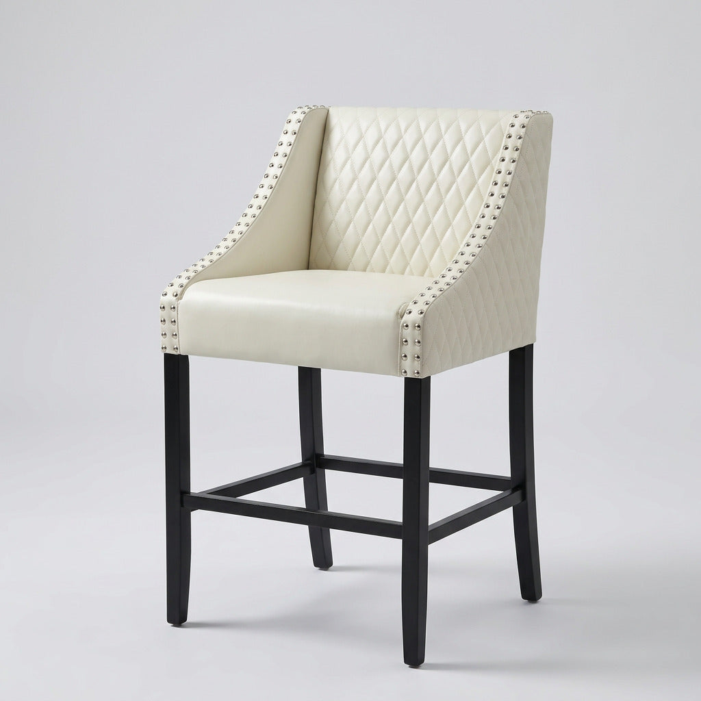 Cream diamond-tufted faux leather bar stool with silver nailhead trim and black wood legs, side view