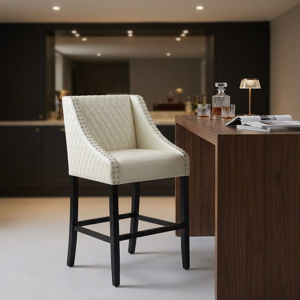 Cream tufted faux leather bar stool with nailhead trim beside a walnut home bar