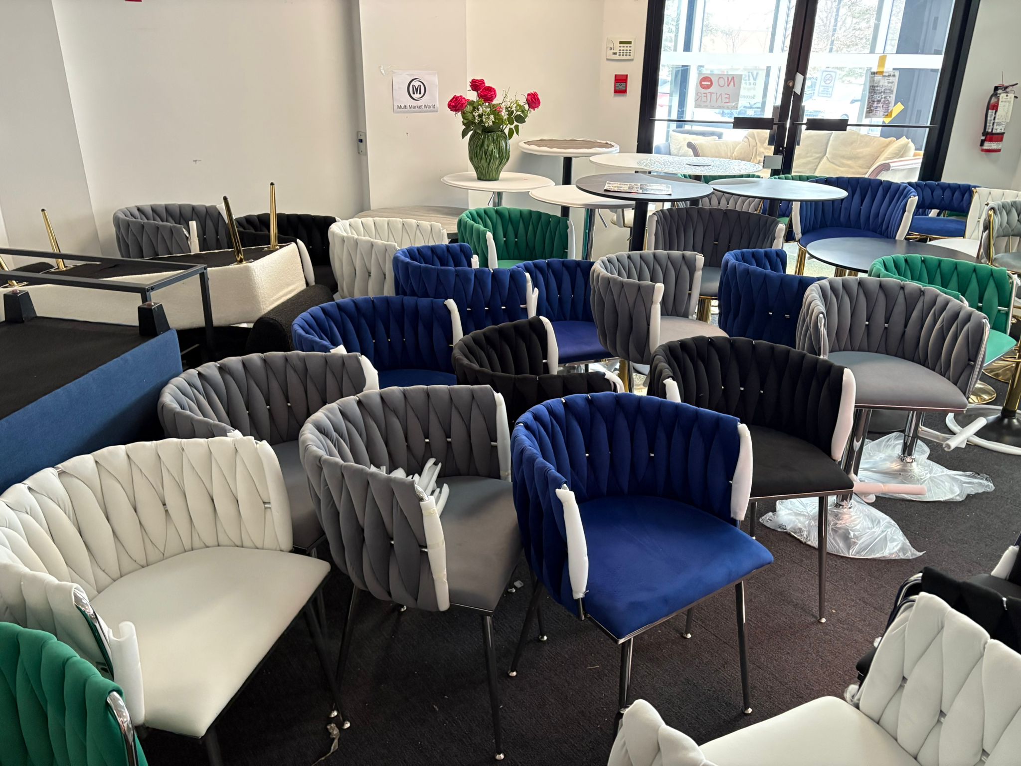 Colorful chairs and tables arranged in a room with a vase of flowers on a table.