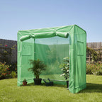 Green garden shelter in a backyard with plants and a wooden fence.